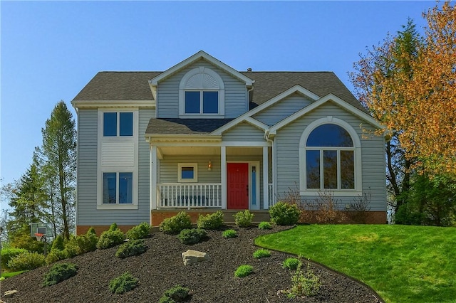 view of front of property featuring covered porch, a shingled roof, and a front lawn