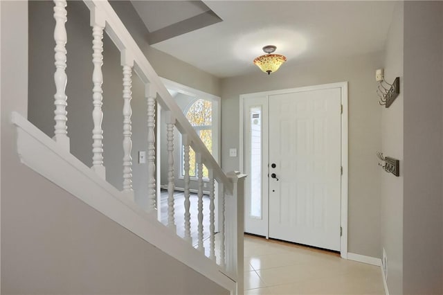 entryway with stairs, baseboards, and light tile patterned floors