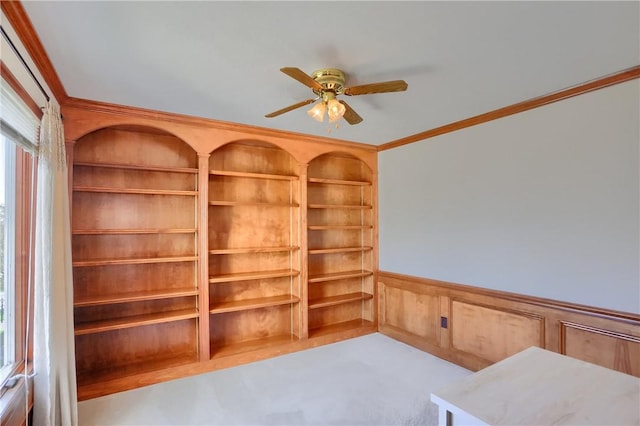 interior space featuring crown molding, a wainscoted wall, and ceiling fan