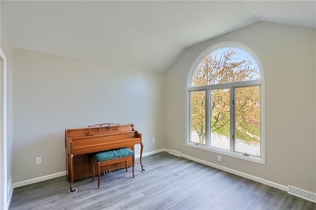 living area with plenty of natural light, vaulted ceiling, and wood finished floors