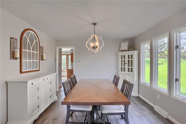 dining room with a wealth of natural light, dark wood finished floors, a chandelier, and visible vents