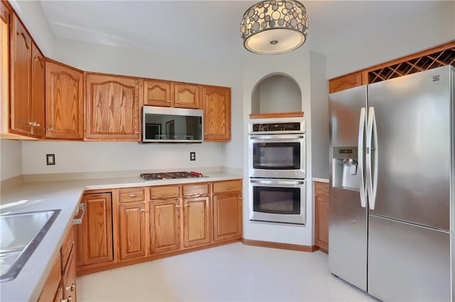 kitchen featuring a sink, appliances with stainless steel finishes, brown cabinets, and light countertops