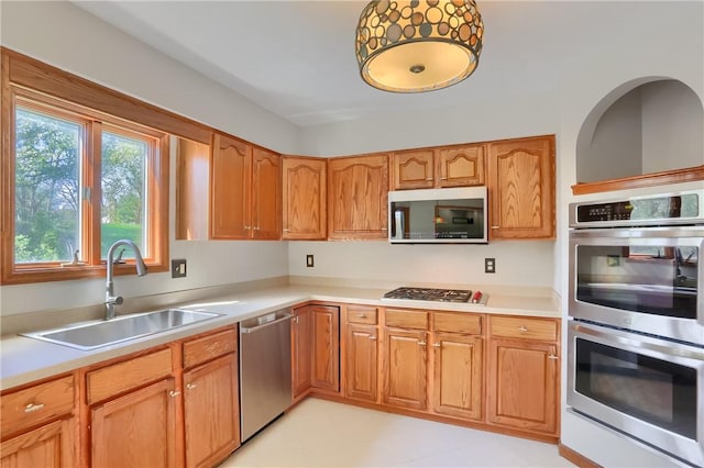 kitchen featuring a sink, appliances with stainless steel finishes, brown cabinetry, and light countertops