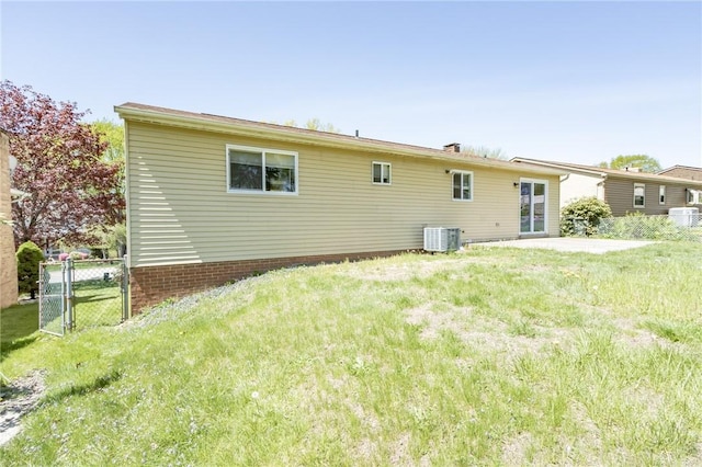 back of house featuring central air condition unit, a yard, fence, and a gate