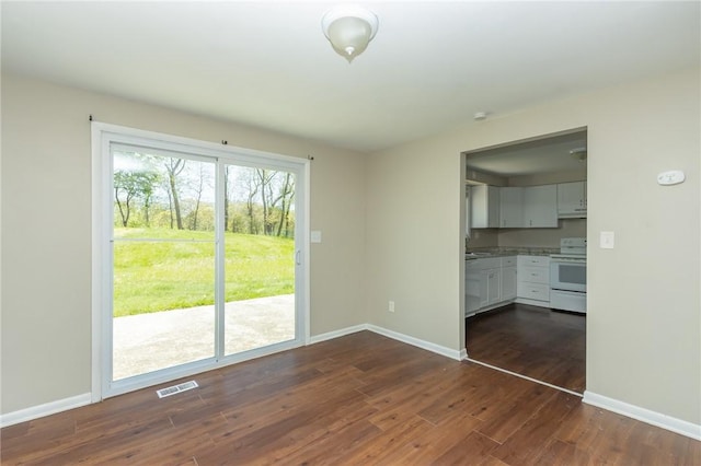 unfurnished living room featuring baseboards, visible vents, and dark wood-style floors