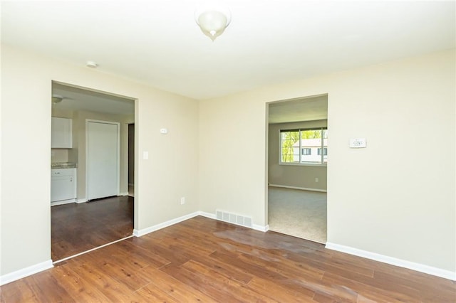empty room with baseboards, visible vents, and wood finished floors