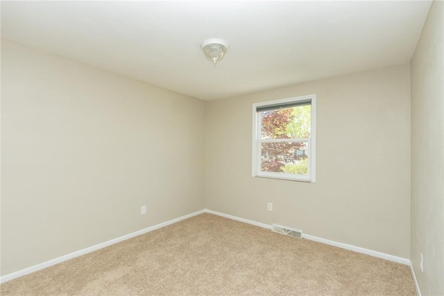 spare room featuring light colored carpet, baseboards, and visible vents