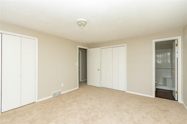 unfurnished bedroom with visible vents, carpet, and multiple closets