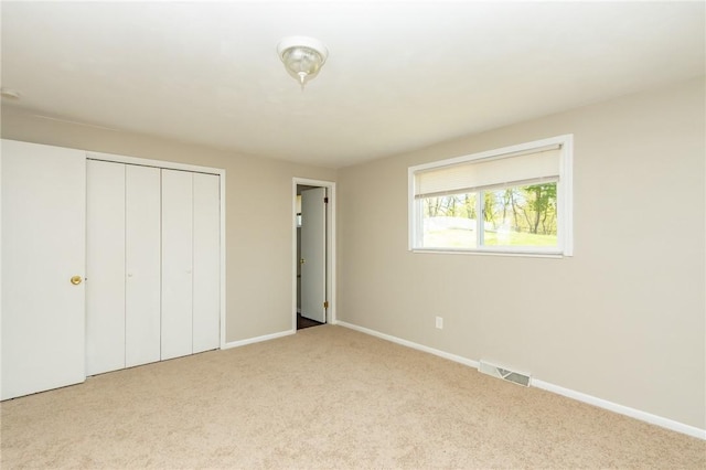 unfurnished bedroom featuring baseboards, carpet, a closet, and visible vents