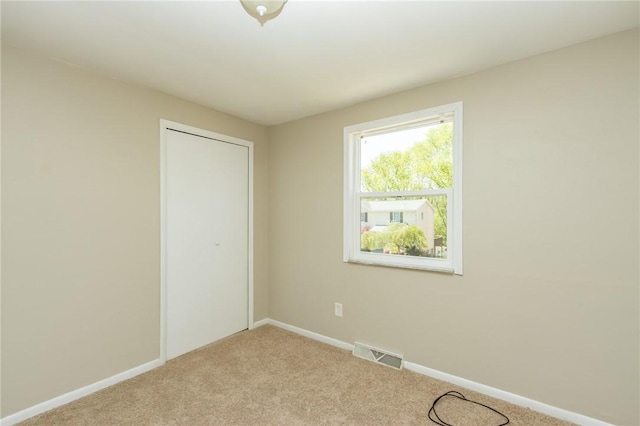 unfurnished bedroom featuring visible vents, carpet flooring, baseboards, and a closet