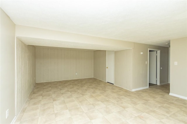 basement featuring baseboards and wood walls