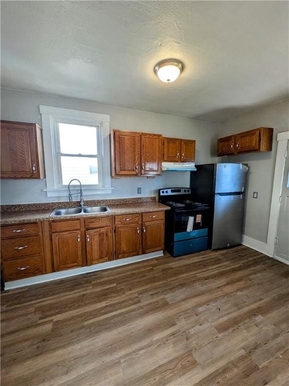 108 Mccandless St, Arnold, PA 15068 - kitchen featuring brown cabinetry, freestanding refrigerator, under cabinet range hood, a sink, and black / electric stove