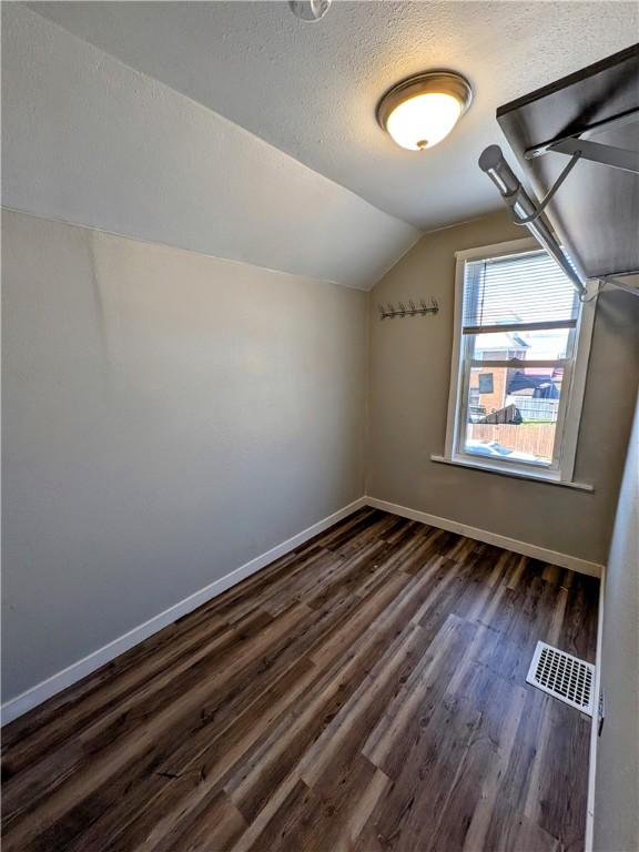 108 Mccandless St, Arnold, PA 15068 - additional living space featuring visible vents, lofted ceiling, baseboards, dark wood-type flooring, and a textured ceiling