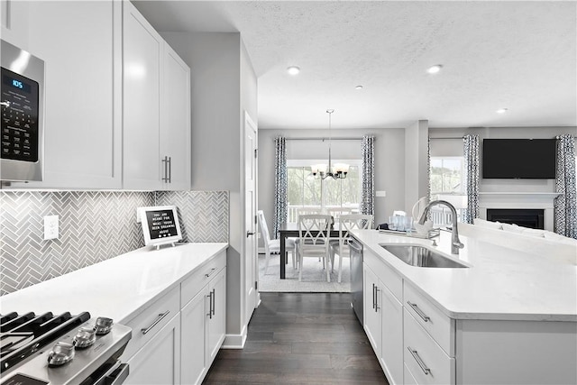 kitchen featuring dark wood-style flooring, a notable chandelier, a sink, light countertops, and stainless steel appliances