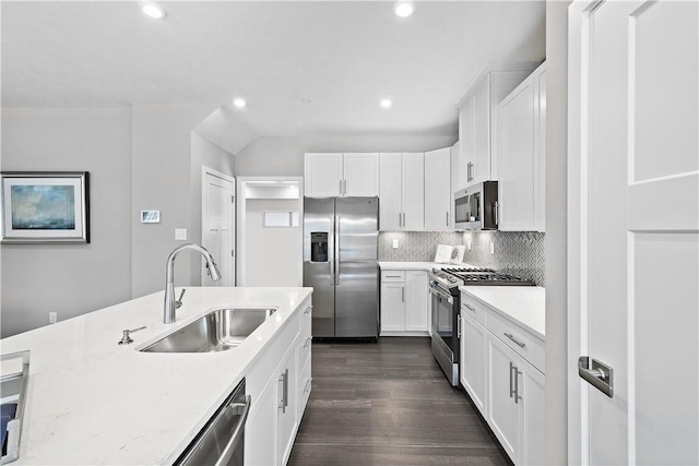 kitchen with tasteful backsplash, dark wood finished floors, a sink, white cabinets, and stainless steel appliances