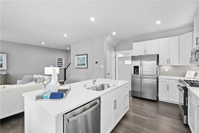 kitchen featuring appliances with stainless steel finishes, a center island with sink, a sink, dark wood-style floors, and open floor plan