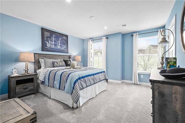 carpeted bedroom featuring recessed lighting, baseboards, and multiple windows