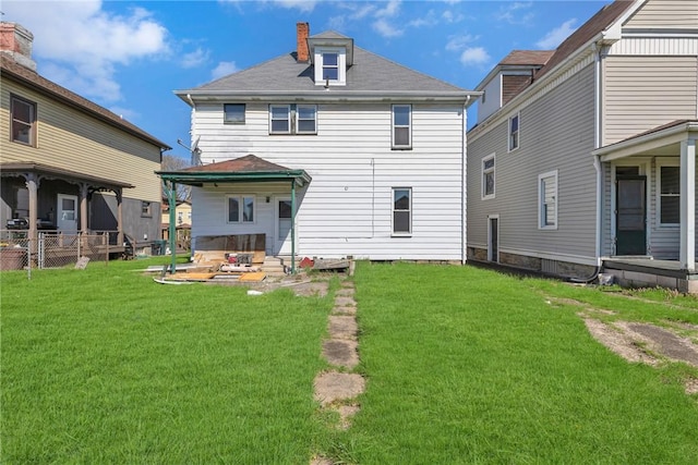 rear view of property featuring a chimney and a yard