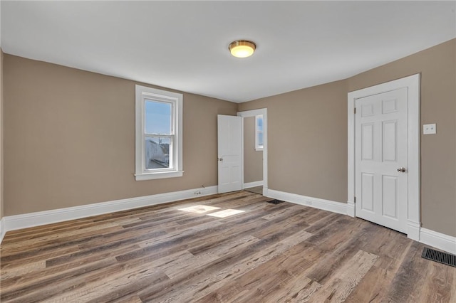 unfurnished room with baseboards, visible vents, and wood finished floors
