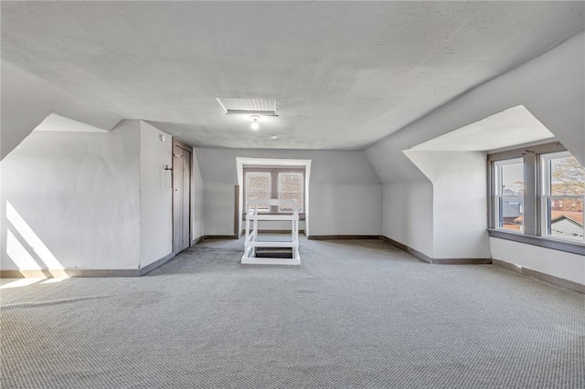 bonus room featuring baseboards, light carpet, lofted ceiling, and plenty of natural light