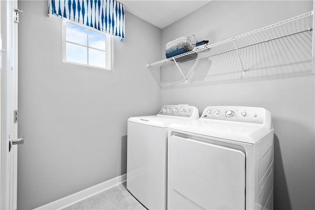 clothes washing area with washing machine and clothes dryer, laundry area, baseboards, and tile patterned floors