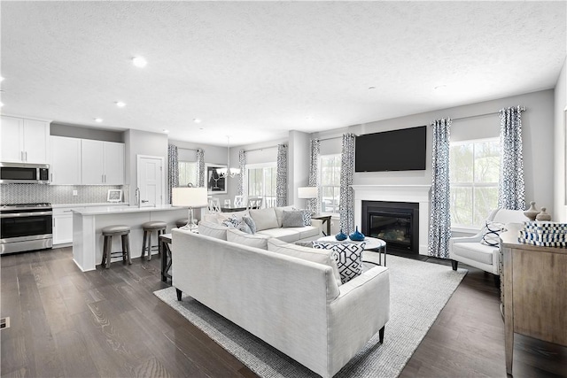 living area with plenty of natural light, recessed lighting, a textured ceiling, and dark wood-style floors