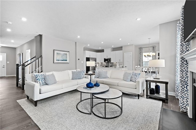 living room with an inviting chandelier, recessed lighting, dark wood-style flooring, and stairs
