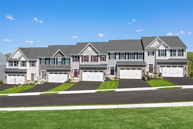 view of front of property featuring an attached garage, driveway, a front lawn, and stone siding