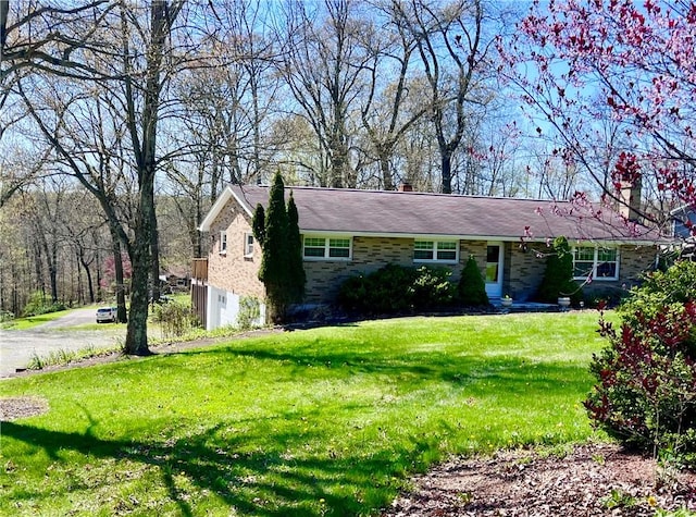 single story home with a chimney, a front lawn, and stone siding