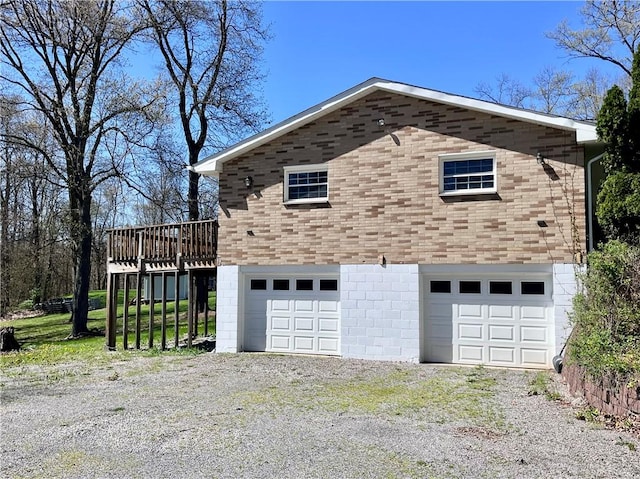 view of side of home featuring an attached garage, driveway, and a deck