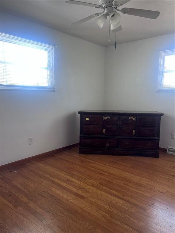 empty room featuring baseboards, ceiling fan, and dark wood-style flooring