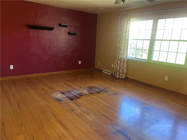 empty room featuring visible vents, a ceiling fan, and wood finished floors