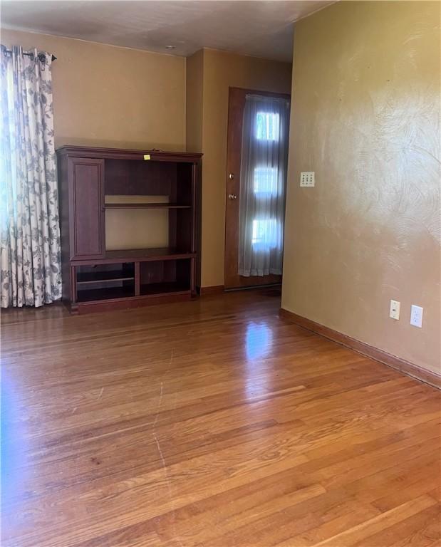 unfurnished living room featuring baseboards and light wood finished floors
