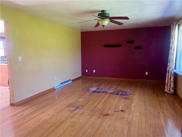 unfurnished room with light wood-style floors, a ceiling fan, baseboards, and a healthy amount of sunlight