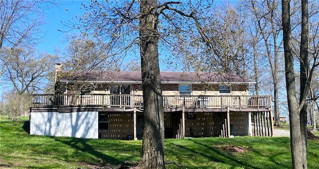 rear view of property featuring a lawn, a chimney, and a deck
