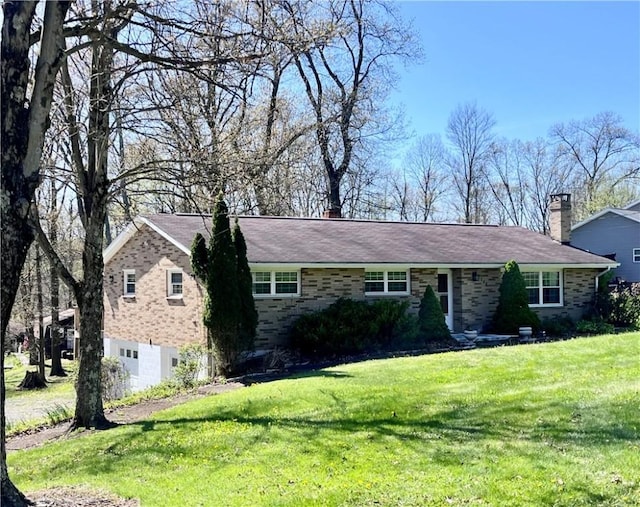 single story home with brick siding, a front lawn, and a chimney