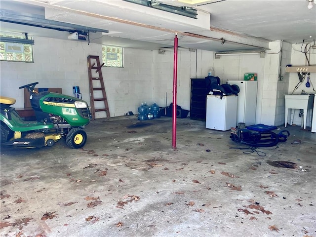 garage with concrete block wall, refrigerator, a sink, and a garage door opener