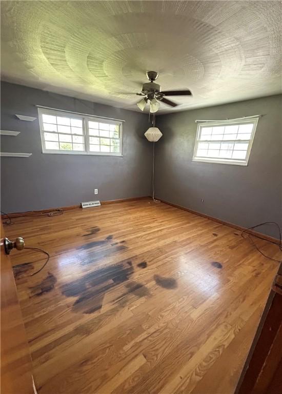 2144 Highland Dr, Summit Twp But, PA 16002 - empty room with a ceiling fan, visible vents, a wealth of natural light, and wood finished floors
