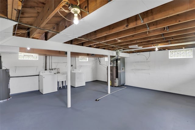basement featuring heating unit, water heater, concrete block wall, and washing machine and clothes dryer