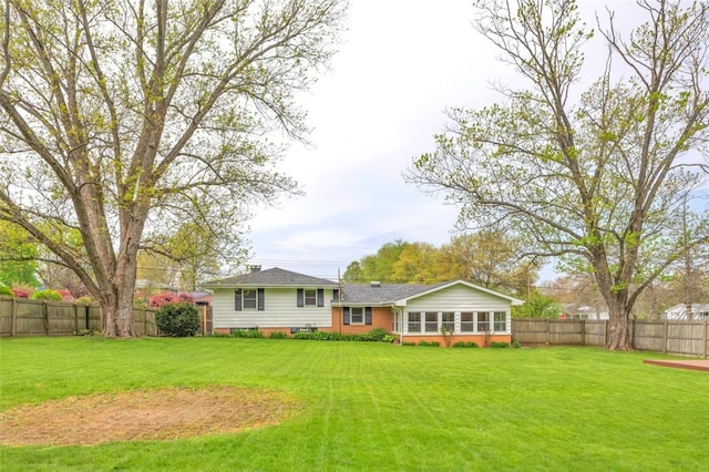 back of house featuring a sunroom, a fenced backyard, and a yard