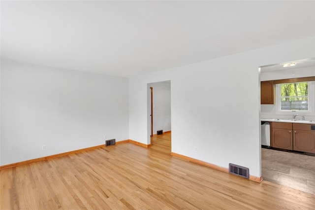 unfurnished living room with visible vents, a sink, and light wood finished floors