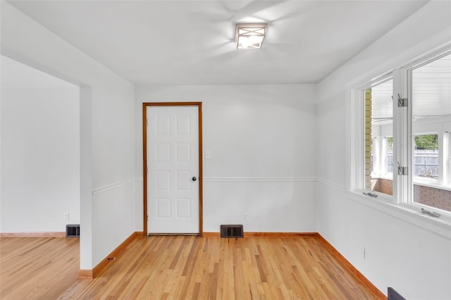 empty room with visible vents, light wood-style flooring, and baseboards