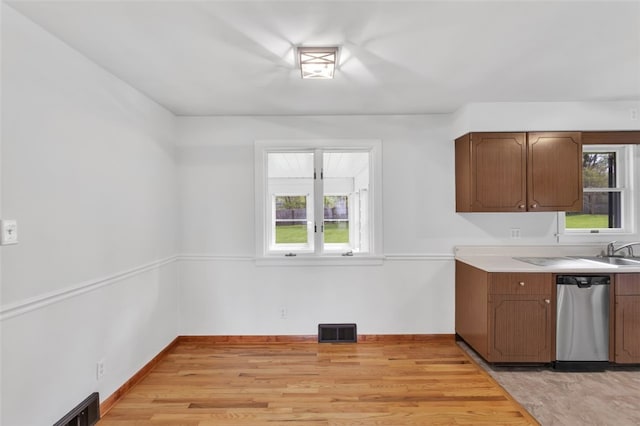 kitchen with stainless steel dishwasher, visible vents, light wood-style flooring, and light countertops