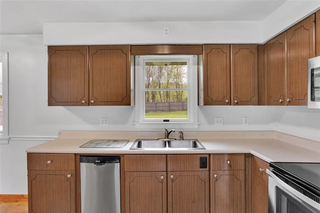 kitchen featuring light countertops, a sink, brown cabinets, and stainless steel appliances