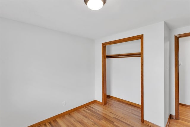unfurnished bedroom featuring a closet, baseboards, and light wood finished floors