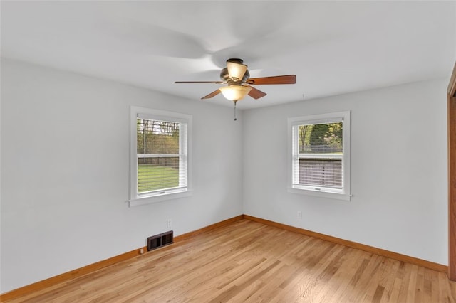 empty room with a healthy amount of sunlight, baseboards, and visible vents