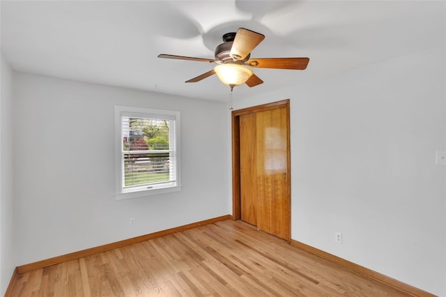 spare room with baseboards, ceiling fan, and light wood-type flooring
