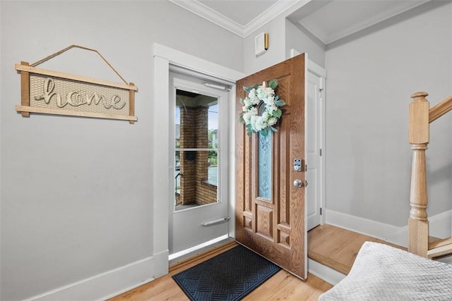 foyer entrance featuring crown molding, baseboards, and wood finished floors