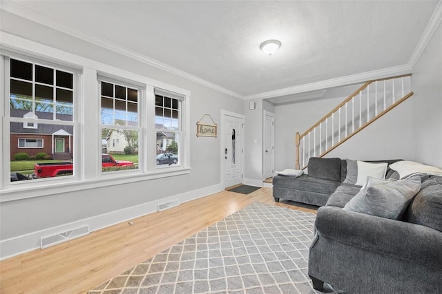 living room featuring baseboards, ornamental molding, wood finished floors, and visible vents