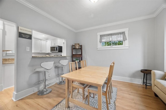 dining area featuring baseboards, ornamental molding, and light wood-style flooring